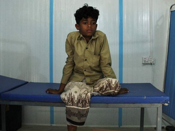 Jemenitischer Junge, dem ein Bein amputiert wurde, sitzt auf einer Pritsche
