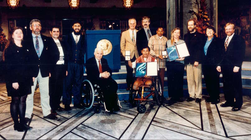 Eine Gruppe lächelnder Menschen gruppiert um das Nobelpreis-Logo