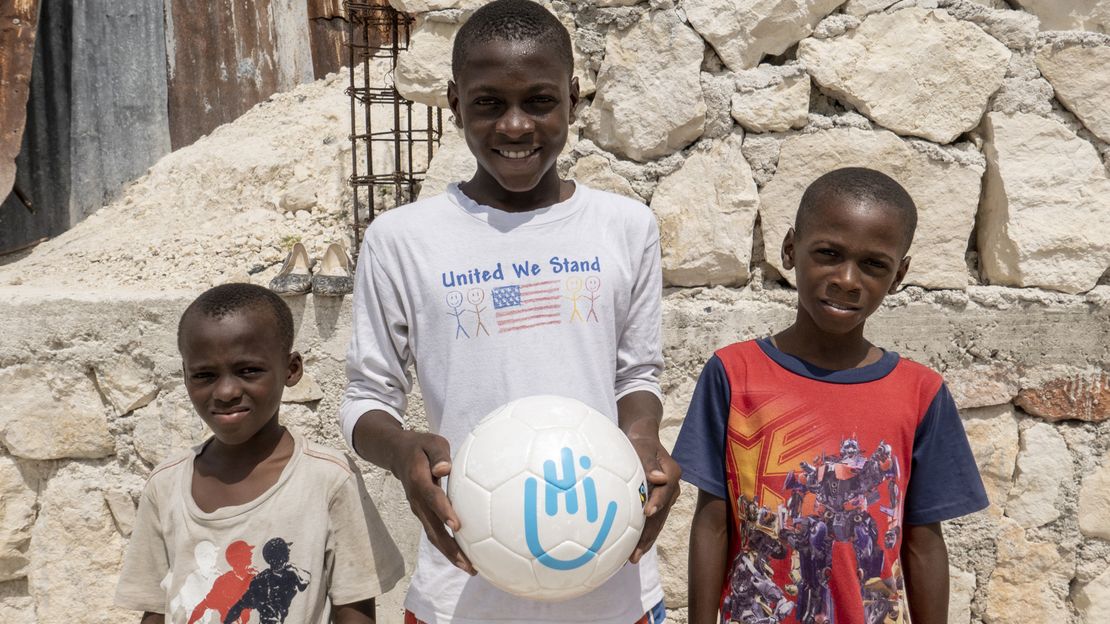 Moise mit seinen Brüdern hält einen Fußball in der Hand.; }}