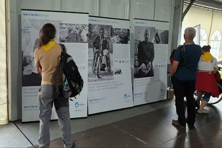 Zwei Menschen stehen vor Ausstellungs-Aufstellern mit Bildern und Texten. 