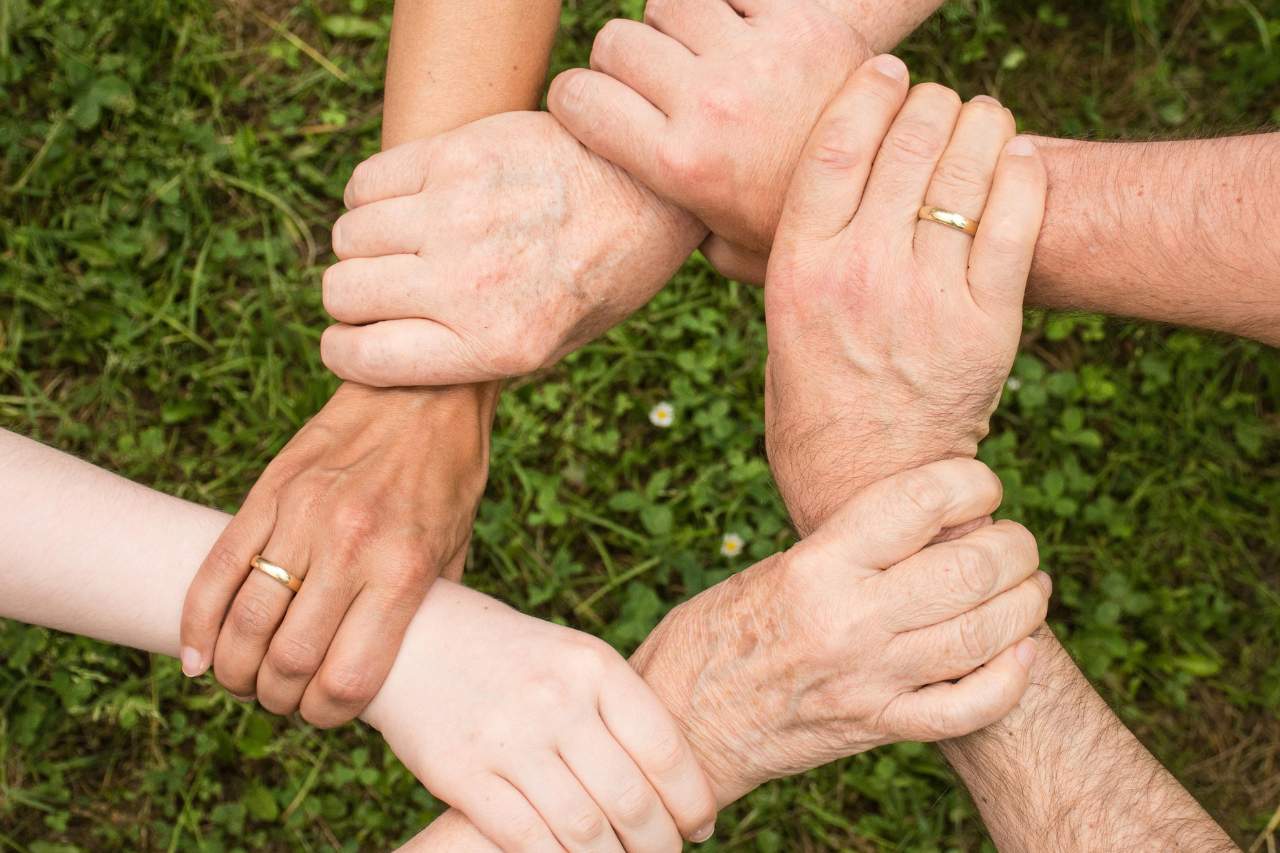 Nahaufnahme verschiedener Menschen, die sich an den Händen halten.