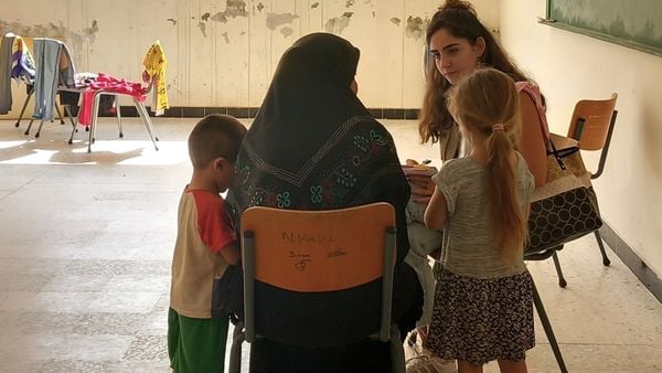 Eine Mutter mit zwei Kindern spricht mit einer Mitarbeiterin von HI in einer zur Flüchtlingsunterkunft umfunktionierten Schule