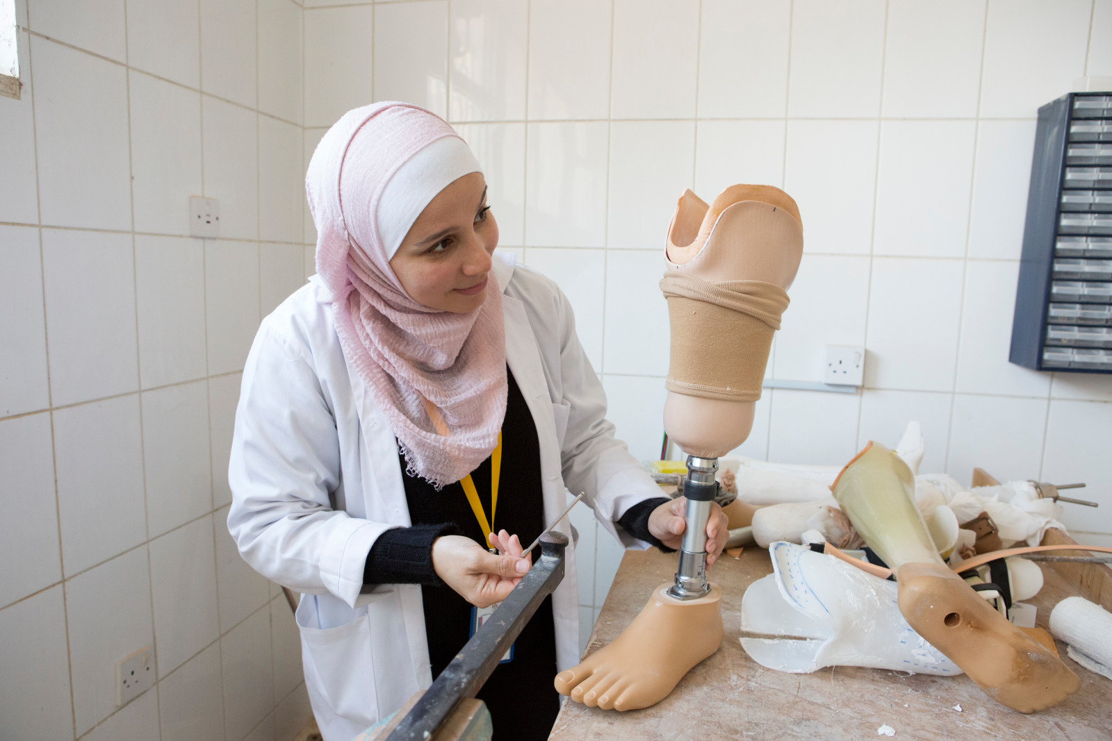 Eine Frau aus Jordanien bearbeitet eine Beinprothese auf einer Arbeitsbank