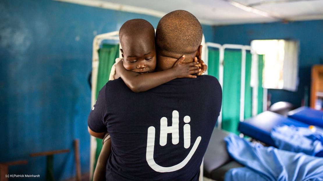 Baby auf dem Arm eines HI-Helfers
